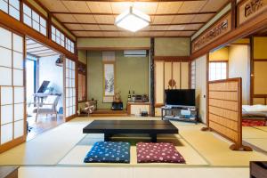 un soggiorno con tavolo e TV di Guest House Enishi a Toyama