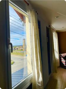 a window with white curtains and a view of a street at Apart Vientos Sureños 2 in Yacimiento Río Turbio