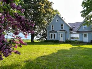 a blue house in a yard with trees and flowers at Garden View near Confederation Bridge and Beaches in Borden-Carleton