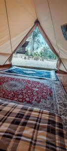 a tent with a bed with a rug in it at Gaharu glamping park in Jerantut