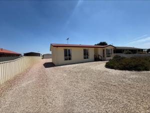 a house with a gravel driveway in front of it at Sea Change Coobowie in Coobowie