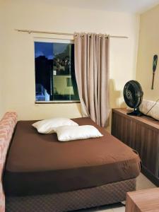 a bedroom with a bed and a window with a fan at Quarto em residência familiar in Navegantes