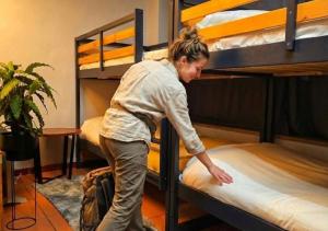 a woman is making a bed in a bunk room at Hostel Cangas Backpackers in Cangas de Morrazo +5 photos