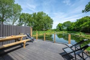 a wooden deck with a table and chairs next to a pond at 5 Bed in Briston oc-2304 in Briston