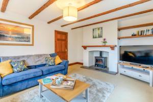a living room with a blue couch and a fireplace at 4 Bed in Tenby oc-vv27177 in Manorbier
