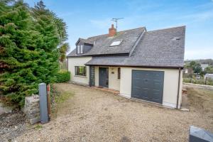 a white house with a black garage at 4 Bed in Tenby oc-vv27177 in Manorbier