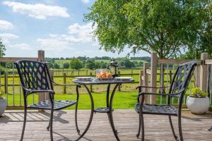 a table and chairs on a deck with a view of a field at 1 Bed in Rolvenden oc-tn612 in Rolvenden +8 photos