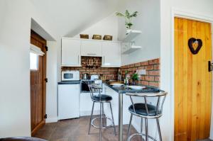 1 Bed in Acle oc-1256 في Cantley: مطبخ بخزائن بيضاء وكراسي بار