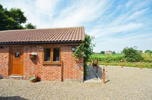1 Bed in Acle oc-1256 في Cantley: منزل صغير مبني من الطوب في ممر مرصوف بالحصى +صورتان