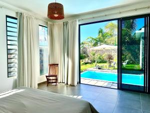 a bedroom with a bed and a view of a pool at Residence Azelina in Pointe aux Canonniers