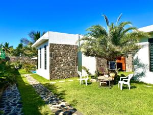 a house with chairs and a palm tree in the yard at Residence Azelina in Pointe aux Canonniers