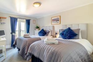two beds in a bedroom with blue pillows on them at 2 Bed in Wells-next-the-Sea oc-2032 in Wells next the Sea