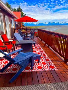 a deck with chairs and tables and an umbrella at Oceanhouse in Homer