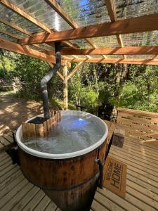 a wooden hot tub sitting under a wooden pergola at Oasis Tiny House & Tinaja in Pichare