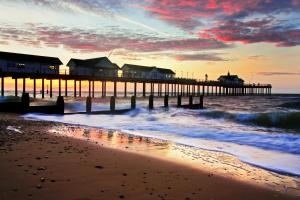 a beach with a pier and the ocean at 2 Bed in Walberswick oc-hhock in Walberswick +2 photos