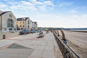a bench on a sidewalk next to the beach at 3 Bed in Broad Haven oc-t30529 in Broad Haven