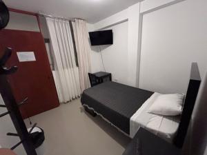 a bedroom with a bed and a door with a television at Hotel Munay in Paracas