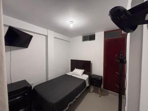 a small bedroom with a bed and a red door at Hotel Munay in Paracas
