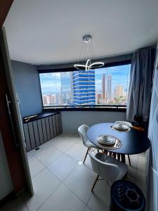 a table and chairs in a room with a large window at Mercure1906 - Piscina aquecida, edifício com estrutura de hotel 4 estrelas in Salvador
