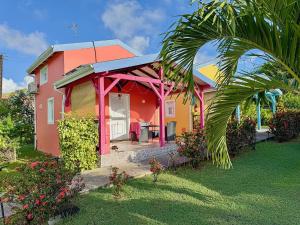 a colorful house with a palm tree in front of it at Bungalows Arc en Ciel in Sainte-Anne