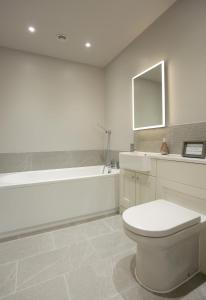 a white bathroom with a toilet and a bath tub at 3 Bed in Barsham oc-bbarn in Beccles +9 photos