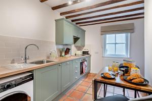 a kitchen with green cabinets and a table with bread on it at 2 Bed in Lavenham oc-f30054 in Lavenham +6 photos