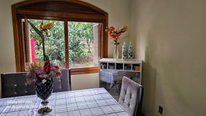 ein Esszimmer mit einem Tisch, auf dem eine Vase mit Blumen steht in der Unterkunft Mimi Nova in Osório