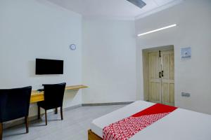 a bedroom with a bed and a desk and a television at Hotel O Dayal Heritage in Hazārībāg