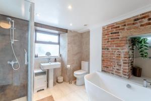 a bathroom with a white tub and a brick wall at 3 Bed in Wooler oc-m31820 in Wooler +15 photos