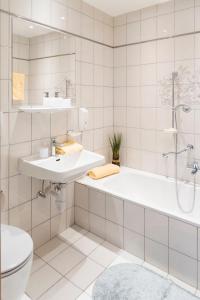 a bathroom with a tub and a sink and a toilet at Hotel Garni Ingeborg in Westendorf