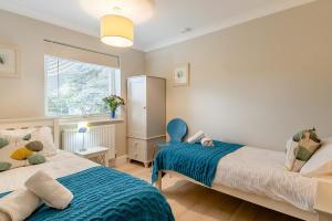 a bedroom with two beds and a blue chair at 3 Bed in Westleton oc-egv in Westleton