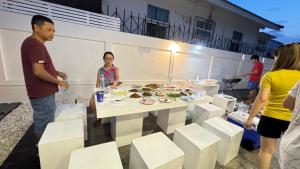 a group of people standing around a table with food on it at แสงจันทร์พลูวิลล่าระยอง in Ban Thung Haeo