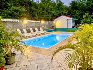 a swimming pool with chairs and a house at Bungalows Arc en Ciel in Sainte-Anne