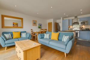 a living room with two blue couches and a kitchen at 2 Bed in Porthleven oc-4stelv in Porthleven
