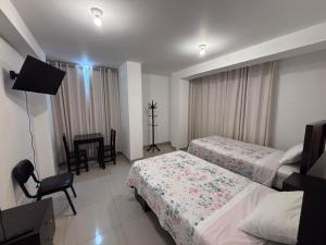a hotel room with two beds and a desk at Hotel Munay in Paracas