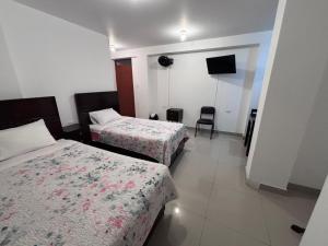 a hotel room with two beds and a television at Hotel Munay in Paracas