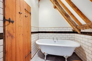a bath tub in a bathroom with a wooden door at 2 Bed in Colkirk oc-1397 in Colkirk +10 photos