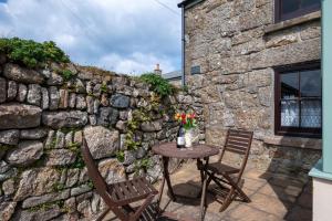 a table and chairs on a patio with a stone wall at 2 Bed in St Just oc-crownm in St. Just