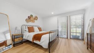 a bedroom with a bed and a large window at Forries Beach Cottage in Wamberal