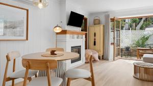 a living room with a table and chairs and a fireplace at Forries Beach Cottage in Wamberal +13 photos