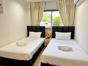 two twin beds in a room with a window at Top Residence Patong in Patong Beach