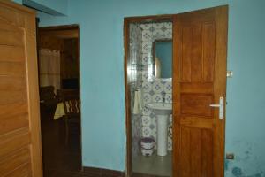 a bathroom with a sink and a mirror and a door at Résidence cosy proche chûtes de la Lobe in Kribi