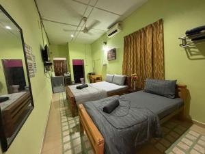 a hotel room with two beds and a television at Studio Khalida Taman Perdana in Pekan
