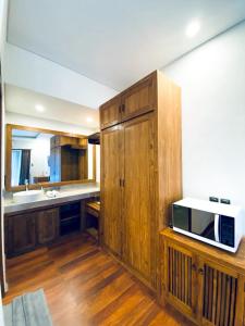 a kitchen with wooden cabinets and a microwave at Indarti Living in Sukawati