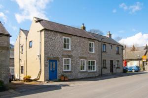 a stone house with a blue door on a street at 4 Bed in Buxton oc-dcjar in Tideswell