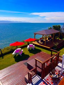 a deck with red umbrellas and chairs and the ocean at Oceanhouse in Homer
