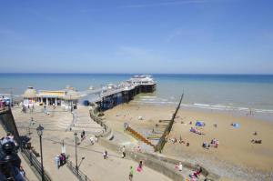 a group of people on a beach near a pier at 1 Bed in Cromer oc-1844 in Cromer