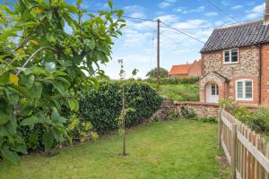a garden with a small tree in front of a house at 2 Bed in Holt oc-2027 in Thornage