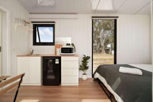 a bedroom with a bed and a kitchen with a microwave at Bellellen Park 1 by Tiny Away in Stawell