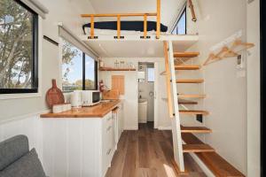 a tiny house with a loft bed and a kitchen at Bellellen Park 2 by Tiny Away in Stawell